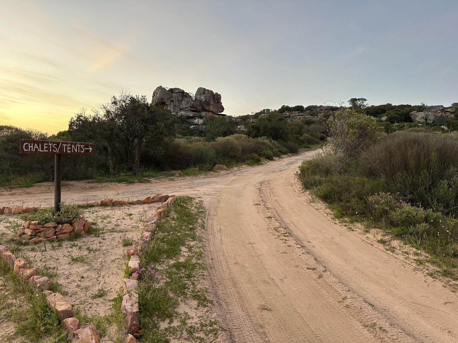 The dirt road into Donkieskraal at golden hour, with the Chalets and Tents sign